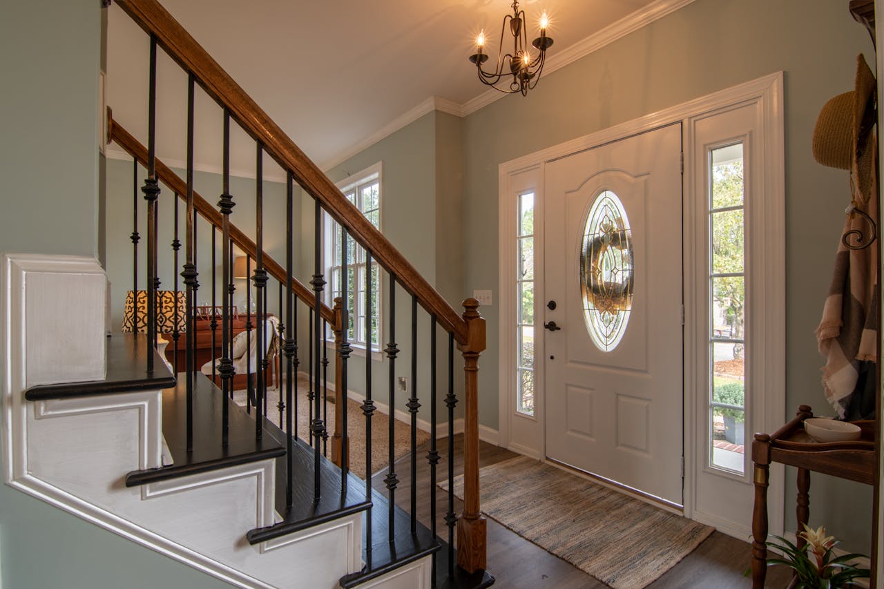 gallery-01 Inviting modern hallway with staircase, chandelier, and natural daylight.